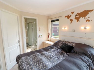 A bedroom with a double bed beside a window and an en suite bathroom at 6 Badgers Retreat in Tunstall near Richmond