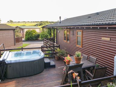 An outdoor deck area with a hot tub table and chairs and potted plants at 6 Badgers Retreat Tunstall near Richmond