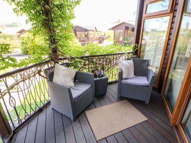 A balcony with two chairs a small table with wine and glasses and plants at 6 Badgers Retreat Tunstall near Richmond