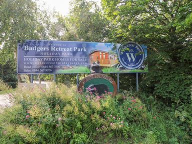 A sign for Badgers Retreat Park holiday park with flowers and bushes around it at 6 Badgers Retreat in Tunstall near Richmond
