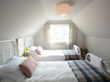 A bedroom with two single beds with plaid blankets and striped pillows at 2 The Dunes Thorpeness