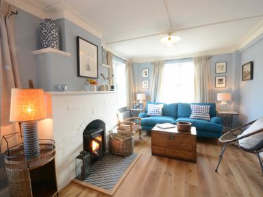 A living room with a blue sofa a fireplace wooden floor and a wooden chest coffee table at 2 The Dunes Thorpeness