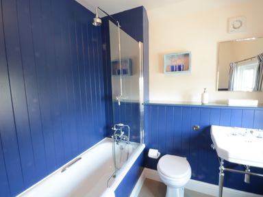 A bathroom with a bathtub shower combo a toilet and a sink at 2 The Dunes Thorpeness