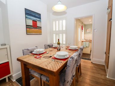 A dining room with a wooden table set for four and a painting on the wall at Holmleigh Aldeburgh