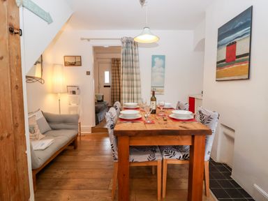 A dining room with a wooden table set with bowls, glasses, and a bottle of wine at Holmleigh Aldeburgh in Aldeburgh