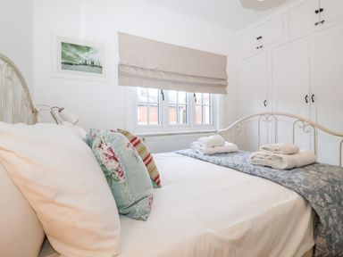 A bedroom with a metal bed frame pillows folded towels and built-in wardrobes at Holmleigh Aldeburgh