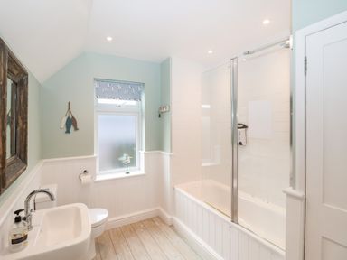 A bathroom with a sink toilet and bathtub with glass shower doors at Holmleigh Aldeburgh in Aldeburgh