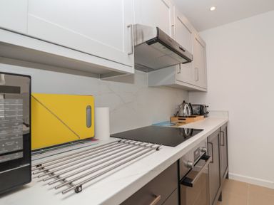 A kitchen countertop with a microwave oven cutting board roll of paper towels electric stove kettle toasters at Holmleigh Aldeburgh
