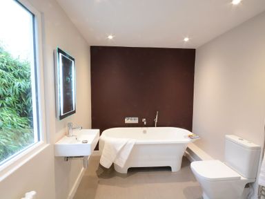 A bathroom with a bathtub a sink a toilet and a window at Durdans Walberswick in Walberswick