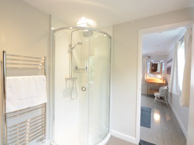 A bathroom with a glass shower enclosure and a towel rack with a white towel at Durdans Walberswick in Walberswick