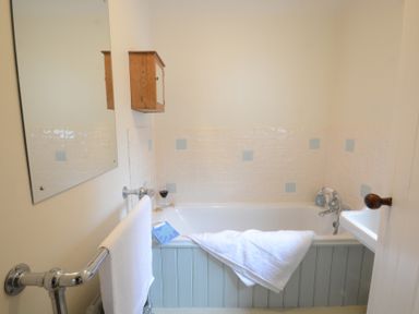 A bathroom with a bathtub white towel on rail and bath at Durdans Walberswick