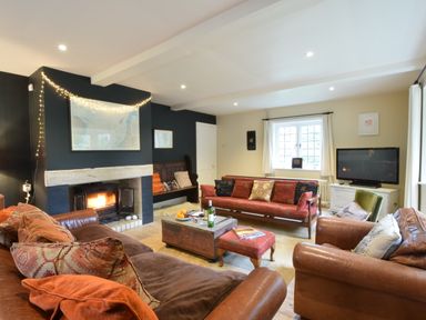 A living room with leather sofas a wooden bench a fireplace and a television at Durdans Walberswick