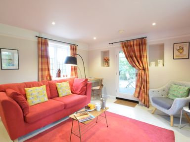 A living room with a red sofa yellow cushions a gray armchair and a coffee table at Durdans Walberswick