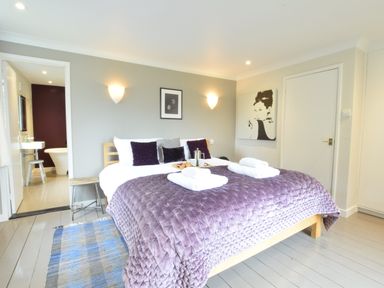 A bedroom with a wooden bed with purple bedding and white towels at Durdans Walberswick in Walberswick