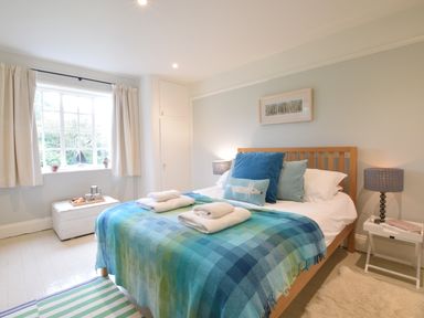 A bedroom with a wooden bed with blue and green checkered blanket and pillows at Durdans Walberswick