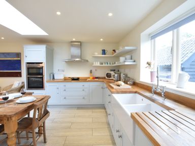 A kitchen with wooden countertops open shelves a dining table and chairs at Durdans Walberswick in Walberswick