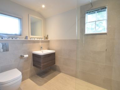 A bathroom with a toilet sink mirror and window at Durdans Walberswick