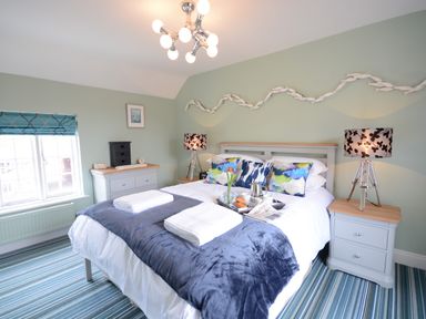 A bedroom with a double bed pillows and bedside tables with lamps at Bunny Cottage Aldeburgh