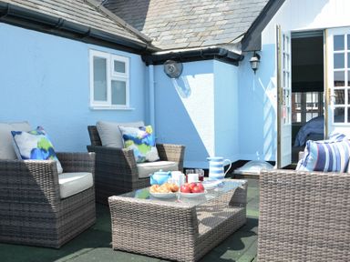 An outdoor patio with wicker chairs and a glass table with breakfast items at Bunny Cottage in Aldeburgh