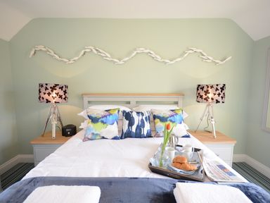 A bedroom with a bed with pillows lamps on bedside tables and a breakfast tray at Bunny Cottage Aldeburgh