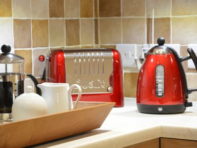 A kitchen countertop with a red toaster, a red electric kettle, a French press, a white milk jug, and a sugar bowl at Red Robin Whepstead Wickhambrook near Bury St Edmunds