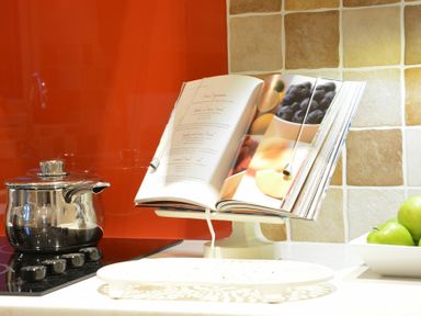 A kitchen counter with a pot on a stove a cookbook on a stand and a bowl of green apples at Red Robin Whepstead in Wickhambrook near Bury St Edmunds