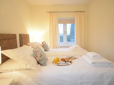 A bedroom with two single beds with white bedding pillows and towels by a window at Red Robin Whepstead Wickhambrook near Bury St Edmunds