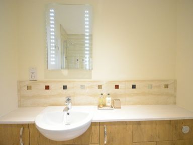 A bathroom sink with a faucet a mirror above and soap bottles on the countertop at Red Robin Whepstead in Wickhambrook near Bury St Edmunds