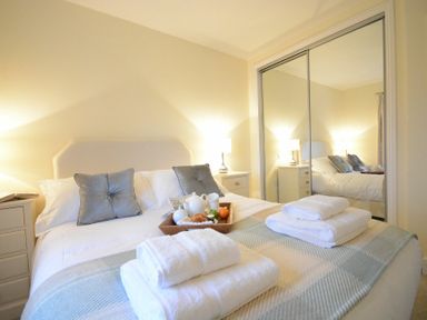 A bedroom with a bed two pillows and a tray with breakfast items at Red Robin Whepstead in Wickhambrook near Bury St Edmunds