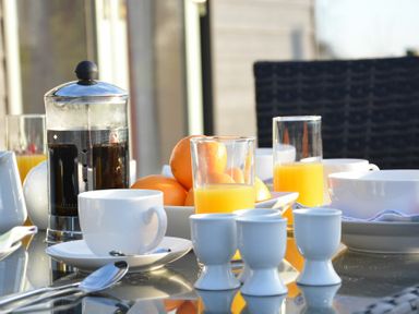 A breakfast table with a French press coffee maker glasses of orange juice eggs and a bowl of oranges at Red Robin Whepstead in Wickhambrook near Bury St Edmunds