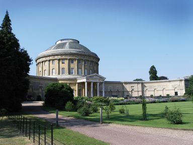 A circular building with columns surrounded by lawns and trees at Red Robin Whepstead in Wickhambrook near Bury St Edmunds