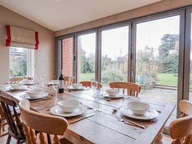 A dining room with a wooden table set for a meal at Holly Lodge in Aldeburgh