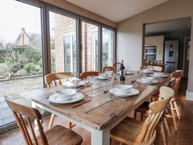 A dining room with a wooden table and chairs at Holly Lodge in Aldeburgh