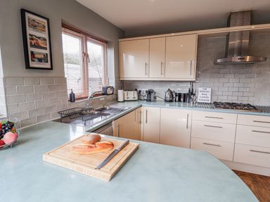 A kitchen with cabinets, sink, and cutting board at Holly Lodge in Aldeburgh