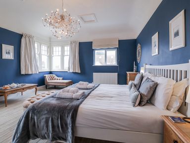 A bedroom with a bed, armchair, and table at Holly Lodge in Aldeburgh