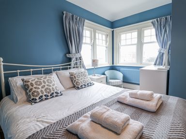 A bedroom with a bed and windows at Holly Lodge in Aldeburgh