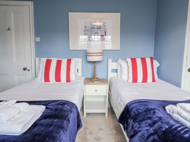 A bedroom with two beds and a lamp on a bedside table at Holly Lodge in Aldeburgh