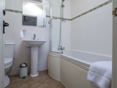 A bathroom with a toilet pedestal sink bathtub and a mirror at Romulus Larling near East Harling