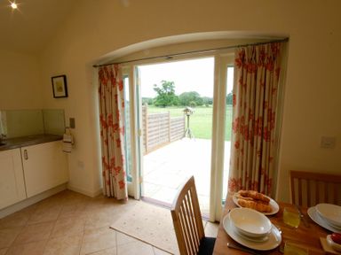 A dining area with a set table next to glass doors leading to a garden at Remus Larling near East Harling