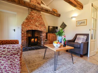 A living room with a brick fireplace wooden coffee table and chairs at Remus in Larling near East Harling