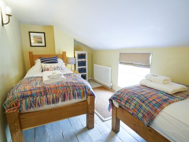 A bedroom with two wooden single beds and a window with a beige blind at Aldeburgh Cottage in Aldeburgh