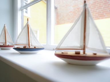 Three small model sailboats on a windowsill with a window showing the outside at Aldeburgh Cottage in Aldeburgh