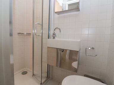 A bathroom with a shower cubicle a sink with a cabinet and a toilet at Mariners Cottage Aldeburgh