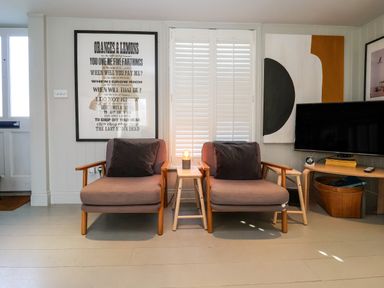 A sitting area with two armchairs a small table with a lamp and a wall-mounted television at Mariners Cottage in Aldeburgh