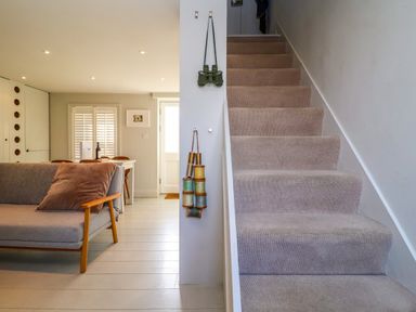 A staircase with carpet and a sofa with a cushion in a living area at Mariners Cottage in Aldeburgh