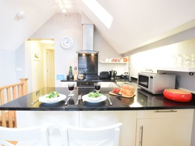 A kitchen with black countertops two place settings and various appliances at Pied a Mer Aldeburgh
