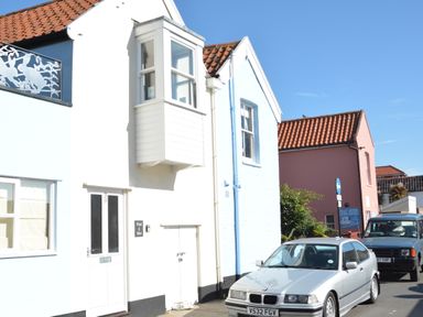A street with white and blue houses with tiled roofs and cars parked in front at Pied a Mer Aldeburgh