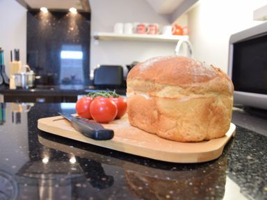 A kitchen countertop with a loaf of bread tomatoes and a knife at Pied a Mer Aldeburgh