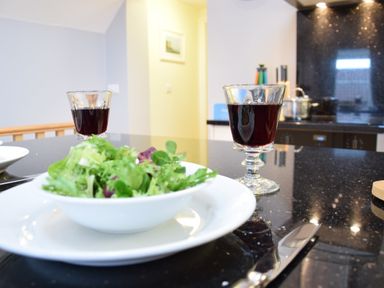 A kitchen counter with a bowl of salad and two glasses of red wine at Pied a Mer Aldeburgh
