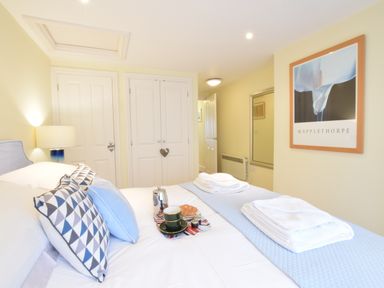 A bedroom with a bed with pillows and folded towels two closed white doors a lamp and a framed picture on the wall at Pied a Mer Aldeburgh